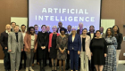 A group of people standing in front of a screen that says Artificial Intelligence