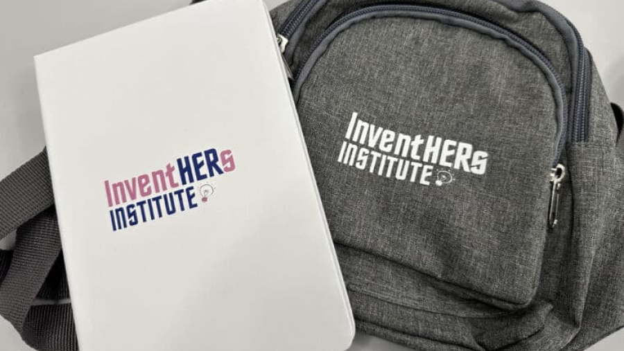 a folder and bag with InventHERs Institute logo